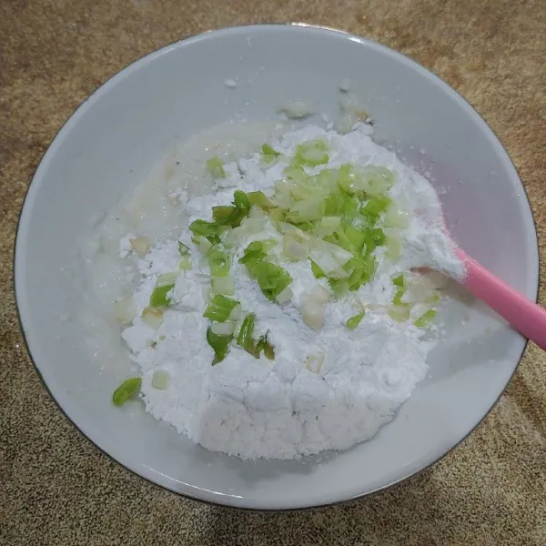 Tambahkan tepung tapioka secara bertahap, kemudian masukkan irisan daun bawang, aduk sampai merata.
