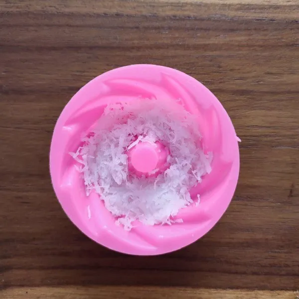 Selagi masih panas, tata kelapa parut di dasar cetakan, padatkan.