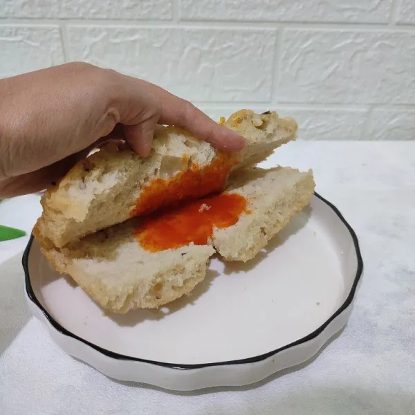 Belah 2 tanpa putus roti lalu oles dengan saos tomat.