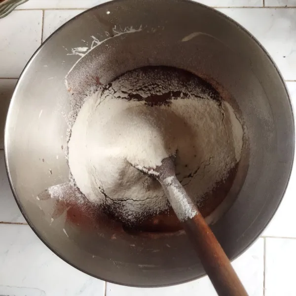 Masukkan tepung terigu, soda kue, maizena, dan garam ke dalam adonan, aduk menggunakan spatula. Tambahkan coklat bubuk dan aduk kembali hingga merata.