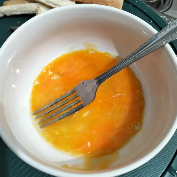 Dalam wadah, kocok telur dengan garpu.