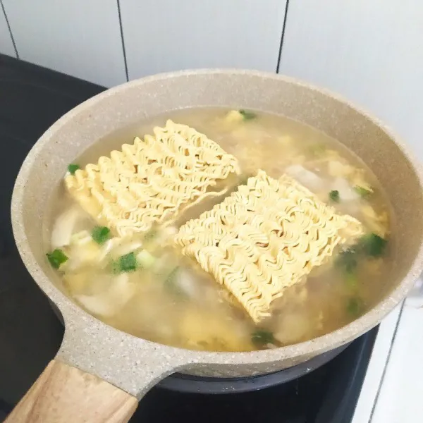 Masukkan 400 ml air dan 2 keping mie. Tutup pancinya lalu masak hingga mie setengah matang.