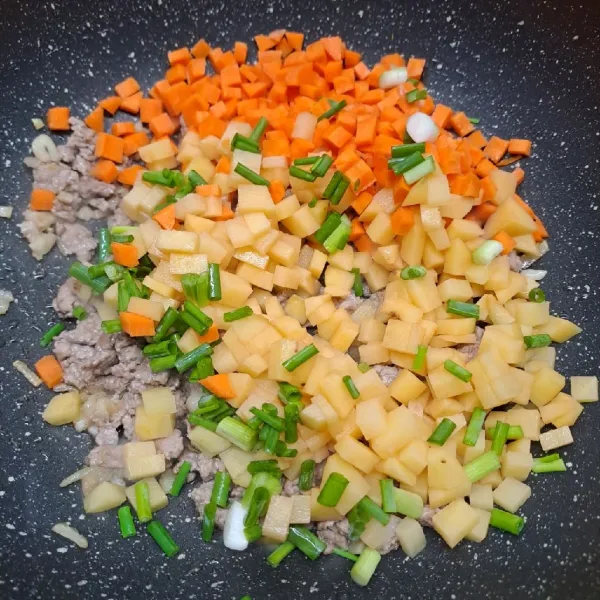 Masukkan kentang, wortel dan daun bawang. Aduk rata dengan tumisan.