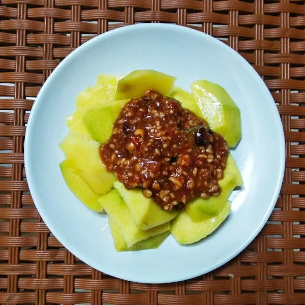 Siapkan piring saji, taruh mangga dan bumbu rujak diatasnya. Rujak mangga siap dinikmati.