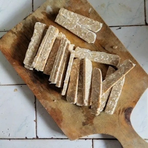 Siapkan tempe, lalu potong tempe berbentuk balok seukuran jari tangan. Setelah itu masukkan ke dalam air lalu tambahkan garam dan penyedap rasa.