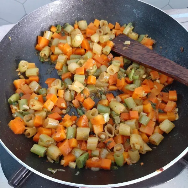 Masukkan wortel dan buncis, tambahkan sedikit air. Masukkan juga irisan daun bawang. Bumbui dengan garam, kaldu bubuk dan bumbu kari. Masak hingga sayuran empuk