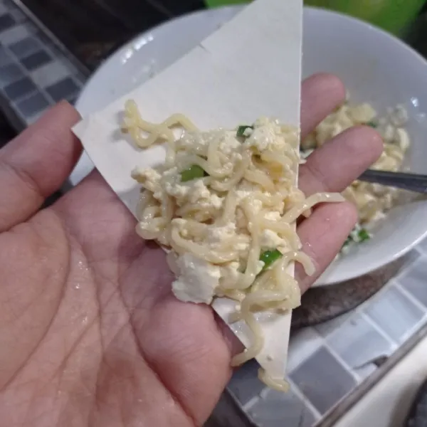 Ambil selembar kulit pangsit beri isian adonan mie tahu, lalu lipat