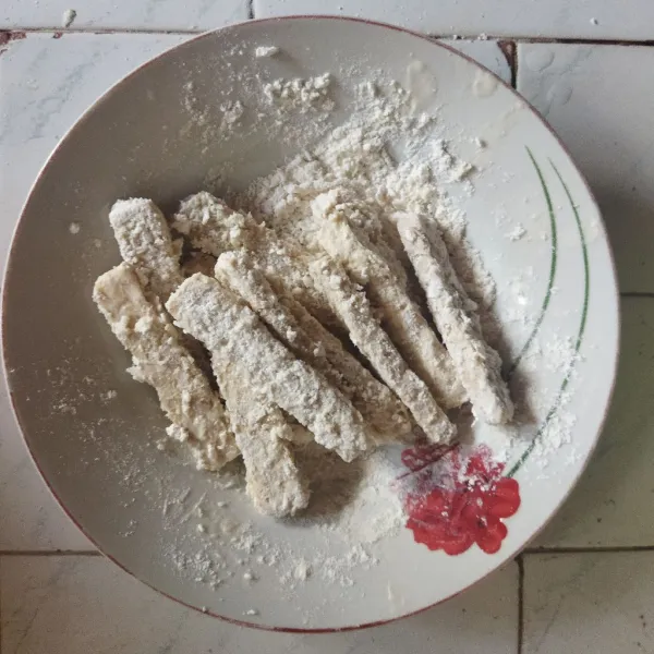 Kocok telur dengan menggunakan garpu lalu balurkan tempe ke dalam telur. Setelah itu balurkan ke dalam campuran tepung hingga terbalut rata.