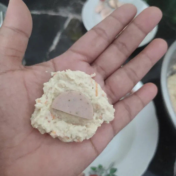 Ambil 1/2 sdm adonan tahu pipih beri isian sosis lalu bulatkan