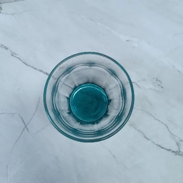 Tuang sirup bunga telang ke dalam gelas.