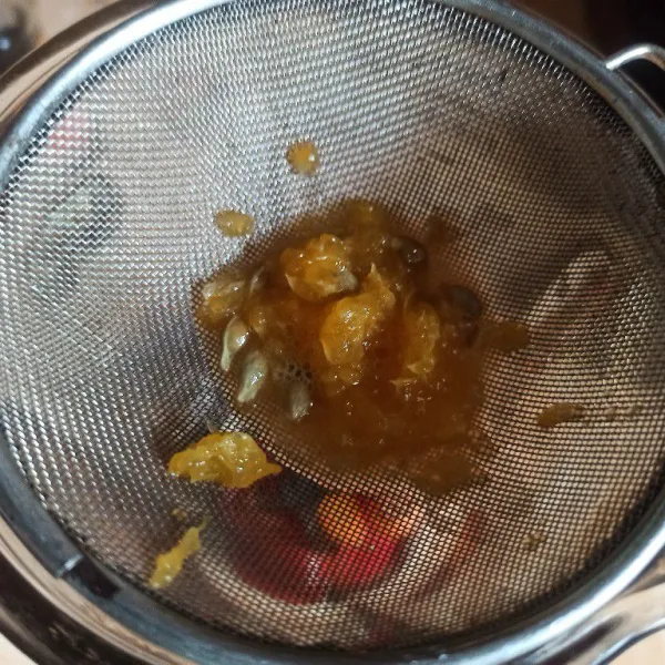 Belah jeruk menjadi 2 bagian kemudian peras sambil disaring, airnya masukkan juga ke dalam blender.