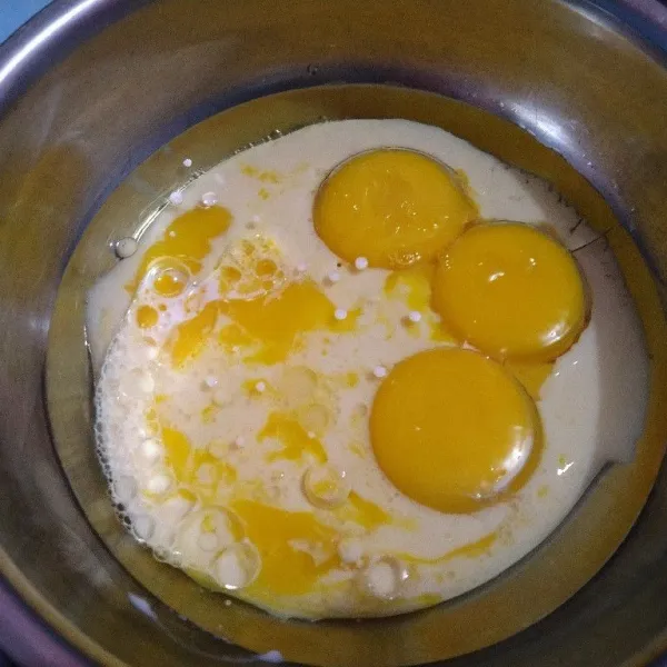 Dalam baskom, masukkan kuning telur, minyak, dan santan, kocok rata pakai whisk.