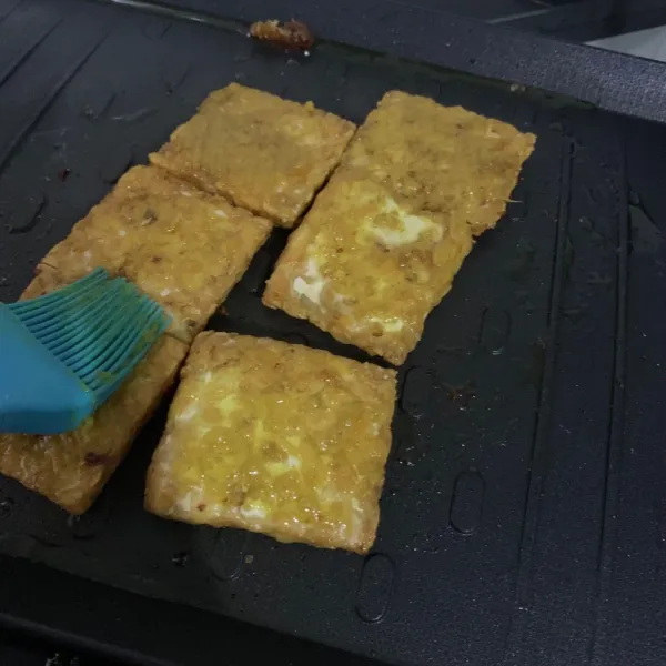 Panggang tempe dan olesi dengan bumbu kuning