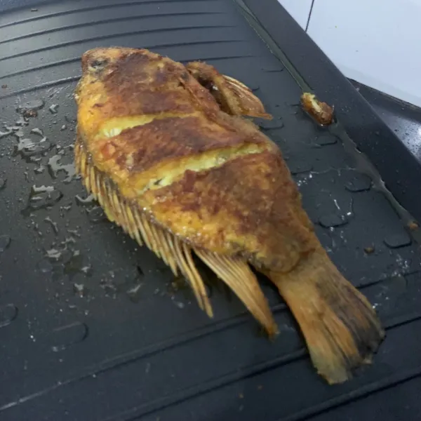 Panggang ikan nila dan olesi dengan bumbu kuning
