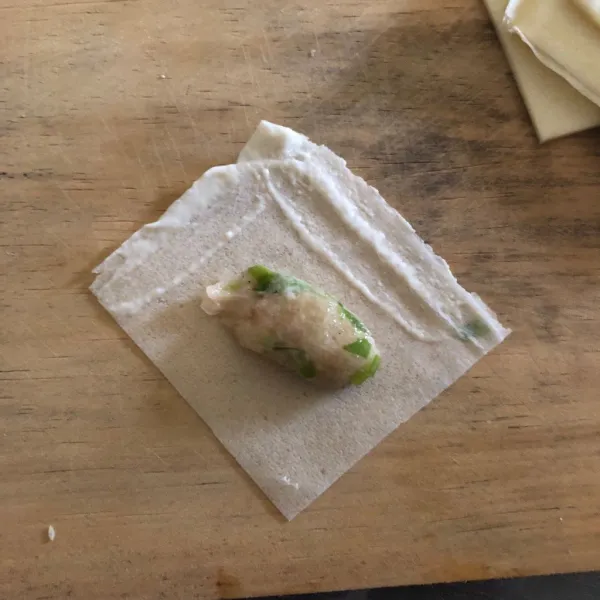 Letakkan adonan ke tengah, lalu berikan perekat di tepi kulit lumpia.