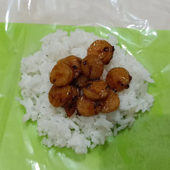 Beri alas dengan plastik atau cetakan onigiri, lalu ambil secukupnya nasi, letakkan isian di tengah-tengah nasi kemudian tutup dengan nasi.