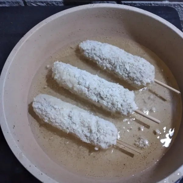 Panaskan minyak di wajan, goreng corn dog dalam minyak panas hingga kecoklatan.