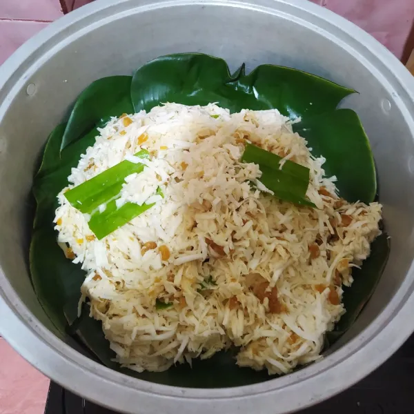 Alasi kukusan dengan daun pisang lalu masukkan campuran singkong dan daun pandan.