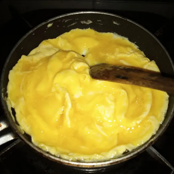 Panaskan satu sendok minyak dalam wajan teflon kecil. Setelah hangat tuang telur. Aduk dari sisi atas kebawah dan bawah keatas. Setelah cukup set/matang tapi bagian atasnya masih basah matikan api.