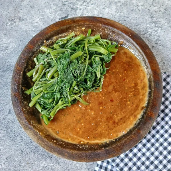 Sajikan kangkung rebus dengan bumbu kacang.