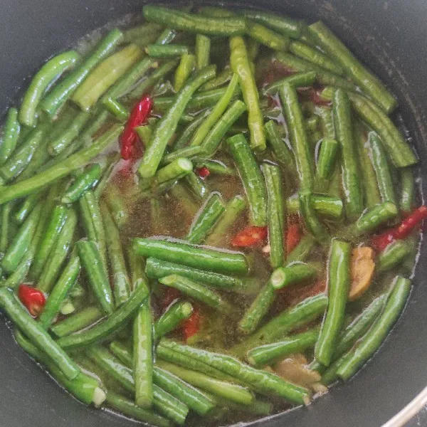 Masukkan air, garam, kaldu, kecap. Masak hingga kacang panjang empuk.