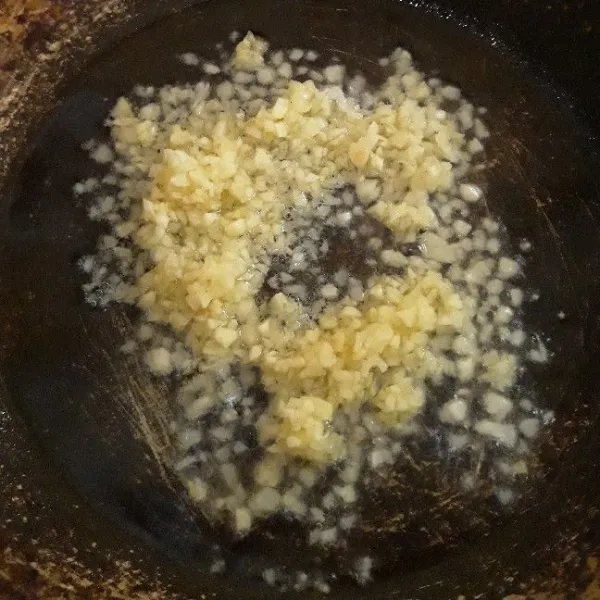 Tumis bawang putih cincang dengan minyak, masak hingga harum