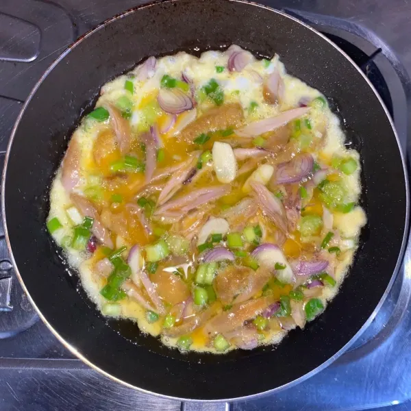 Panaskan minyak, goreng telur dengan api sedang sampai sisi bawah mulai berkulit dan matang.