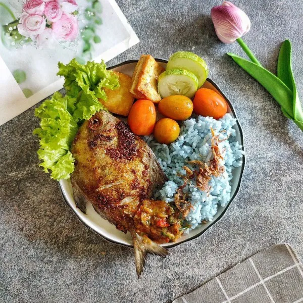 Tata nasi bunga telang di atas piring saji, taburi dengan bawang goreng kemudian sajikan dengan bahan pelengkap lainnya.