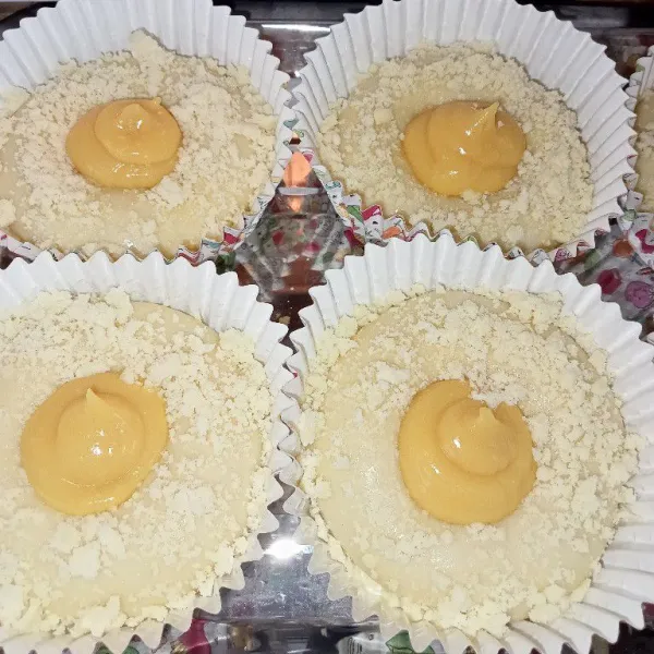Masukkan adonan kedalam cup kertas lalu olesi susu evaporasi, tambahkan taburan crumble dan semprotkan srikaya ditengahnya, proofing kembali selama 60 menit