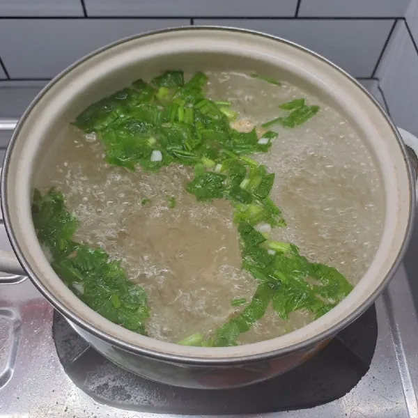 Rebus air, masukkan bawang putih yang dicincang, seledri dan daun bawang sampai mendidih.