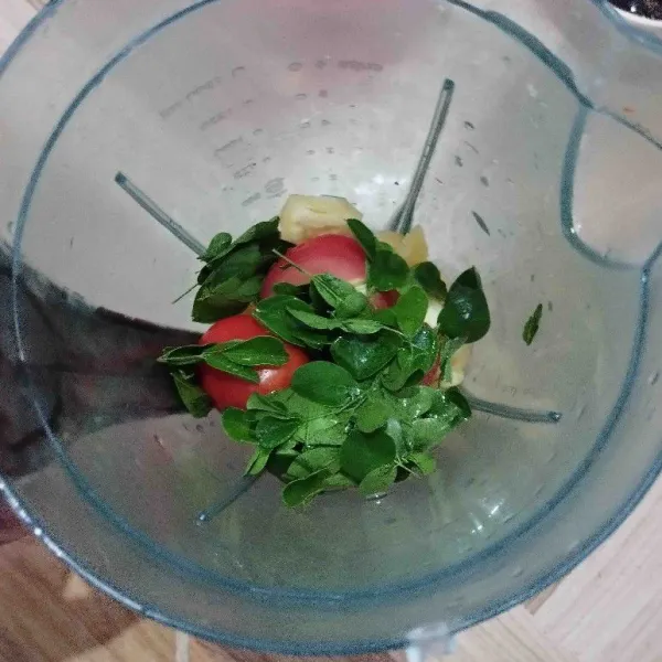 Potong-potong nanas dan tomat. Masukkan buah nanas, tomat, dan daun kelor ke dalam blender.