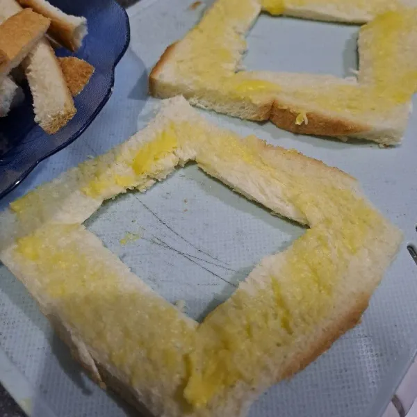 Potong roti tawar bikin kotak ditengahnya  lalu olesi dengan margarine.