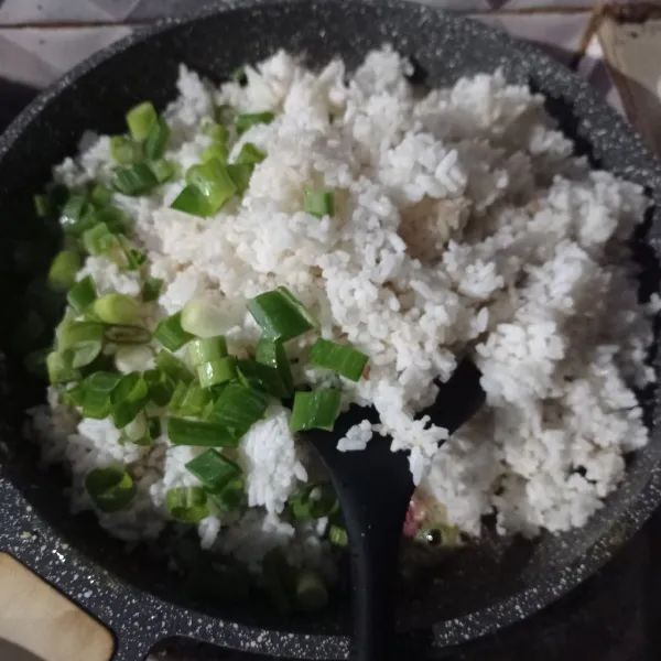 Masukan nasi dan daun bawang, aduk rata