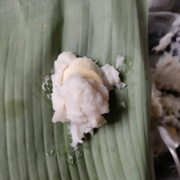 Siapkan selembar daun pisang. Masukkan 1 sdm adonan, letakkan pisang lalu tutup kembali dengan 1 sdm adonan.