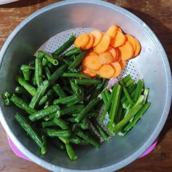 Potong-potong kacang panjang dan iris wortel.