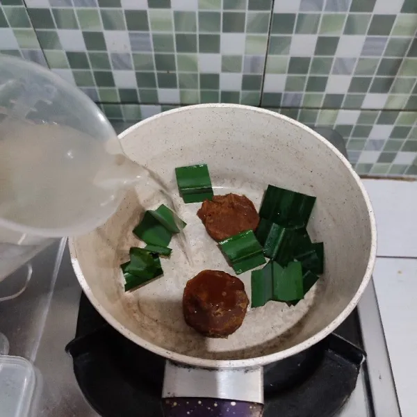 Masukkan gula merah, air dan daun pandan ke dalam wajan.