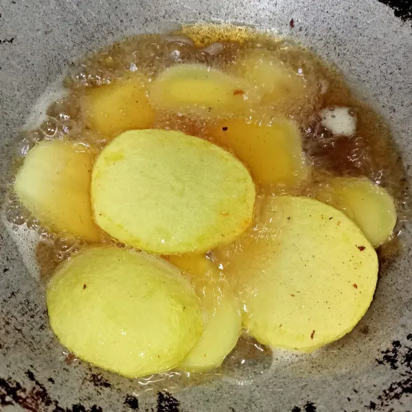 Kupas kentang lalu iris dan goreng kentang hingga berkulit dan matang, goreng juga bawang merah dan bawang putih.