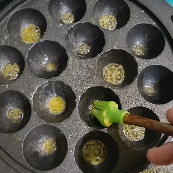 Panaskan loyang takoyaki. Oles dengan margarin.