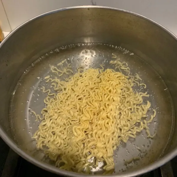 Didihkan air. Masukkan mie telur. Rebus hingga setengah matang. Lalu tiriskan.