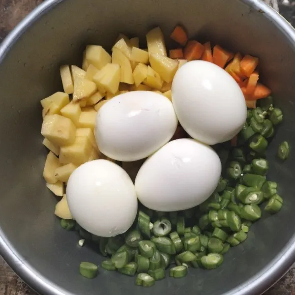 Rebus telur, lalu kupas, potong kecil buncis, wortel, dan kentang.