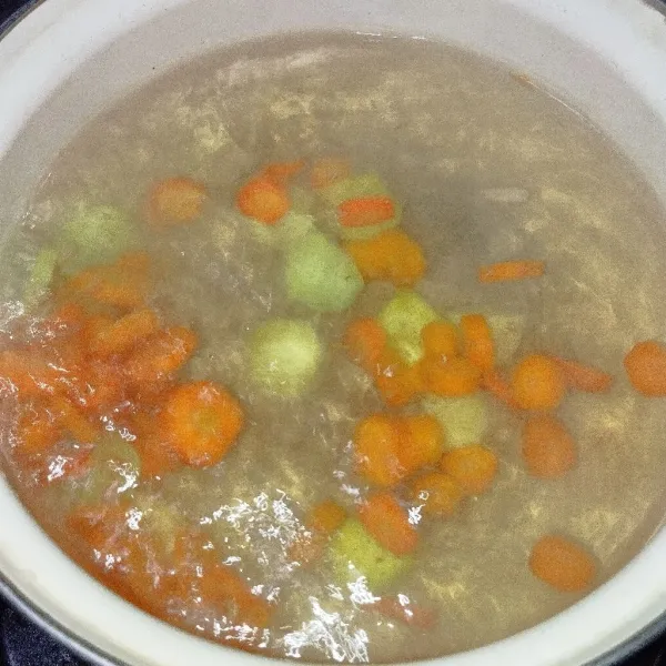 Rebus air hingga mendidih, masukkan kentang dan wortel.