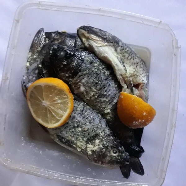 Marinasi ikan mas dengan garam, kaldu bubuk, dan perasan jeruk lemon selama 20 menit.