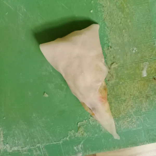 Olesi pinggiranya dengan larutan terigu. Kemudian lipat bentuk segitiga. Lakukan sampai selesai.
