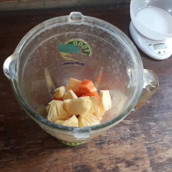 Masukkan pepaya dan nanas ke dalam blender.