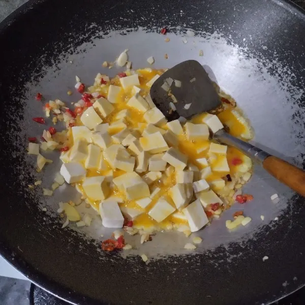 Tuang tahu dan telur. Aduk.