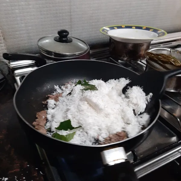 Tambahkan kelapa parut sepertiga bagian dulu, dan daun salam, aduk-aduk hingga mulai memipih atau kandungan air berkurang, tambah lagi sepertiga bagian kelapa, dan oseng oseng lagi hingga air dari kelapa parut berkurang lagi, dan masukan semua sisa kelapa, aduk terus hingga kelapa mulai kecoklatan.