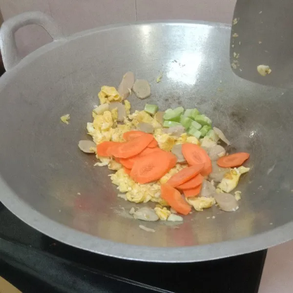 Masukkan bawang putih, bakso, dan sosis.kemudian aduk rata. Lanjutkan dengan memasukkan wortel dan batang-batang brokoli. Aduk rata
