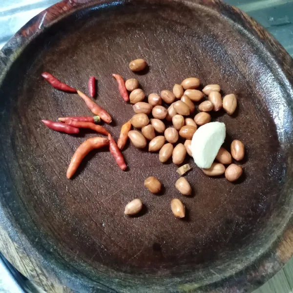 Dalam cobek masukkan kacang tanah, bawang putih dan cabe rawit. Kemudian haluskan.