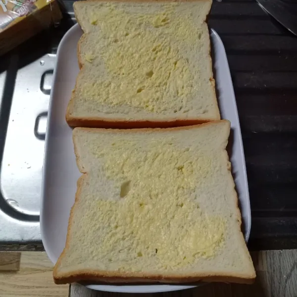 Olesi 1 sisi roti dengan margarin.