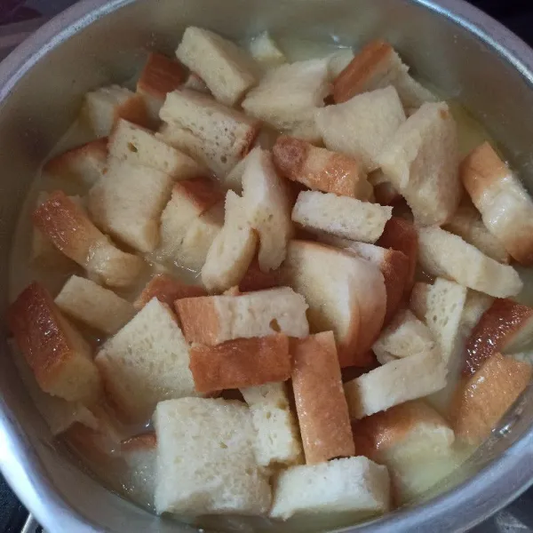 Masukkan roti tawar ke dalam kuah santan aduk rata.